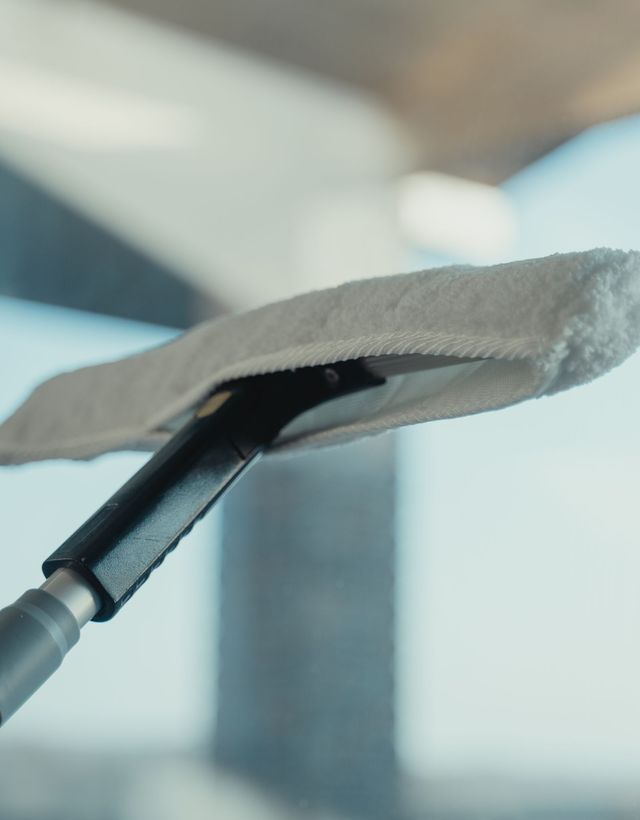 Close-up of a water-fed pole brush resting against clean glass